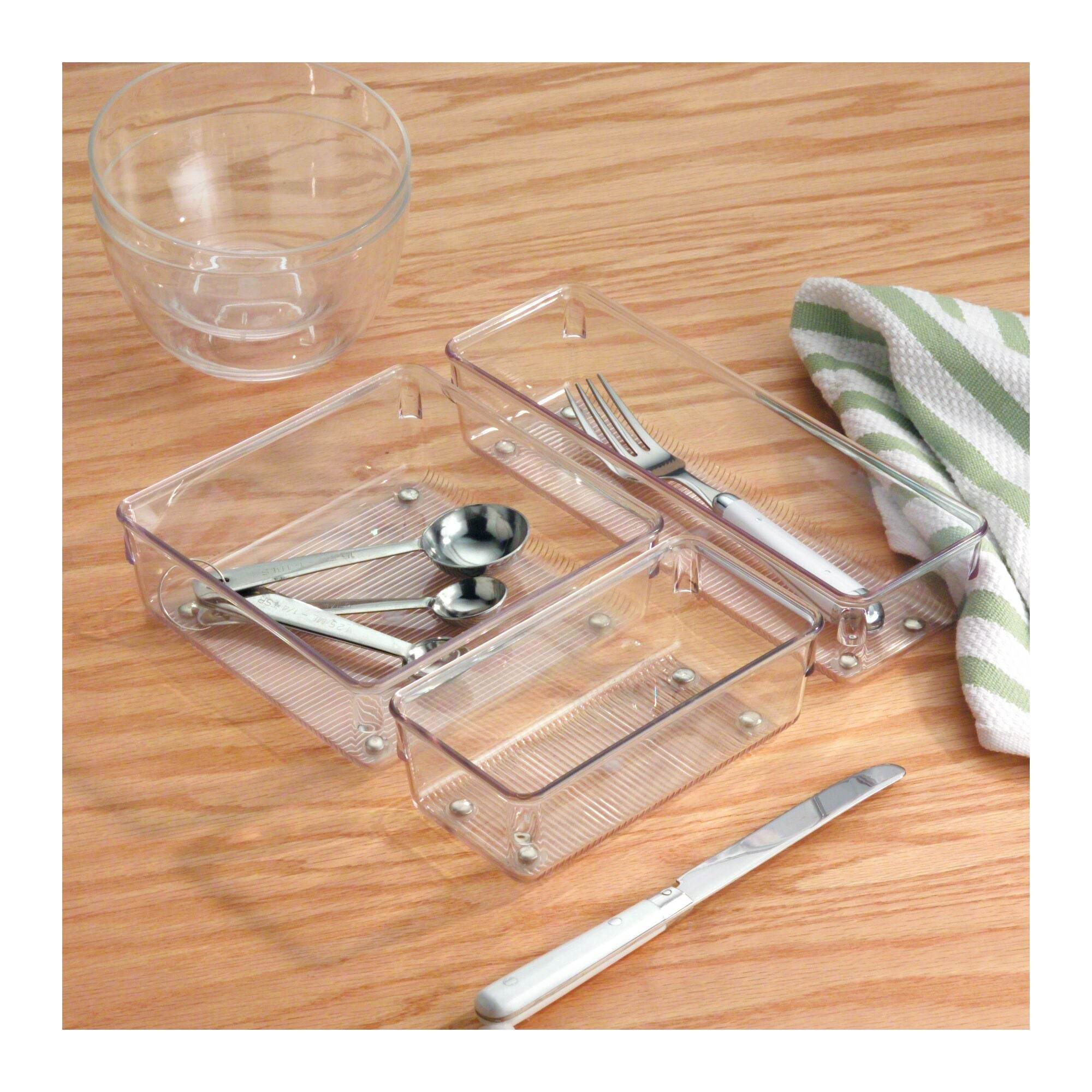 Clear plastic utensil holder with silverware on a wooden surface