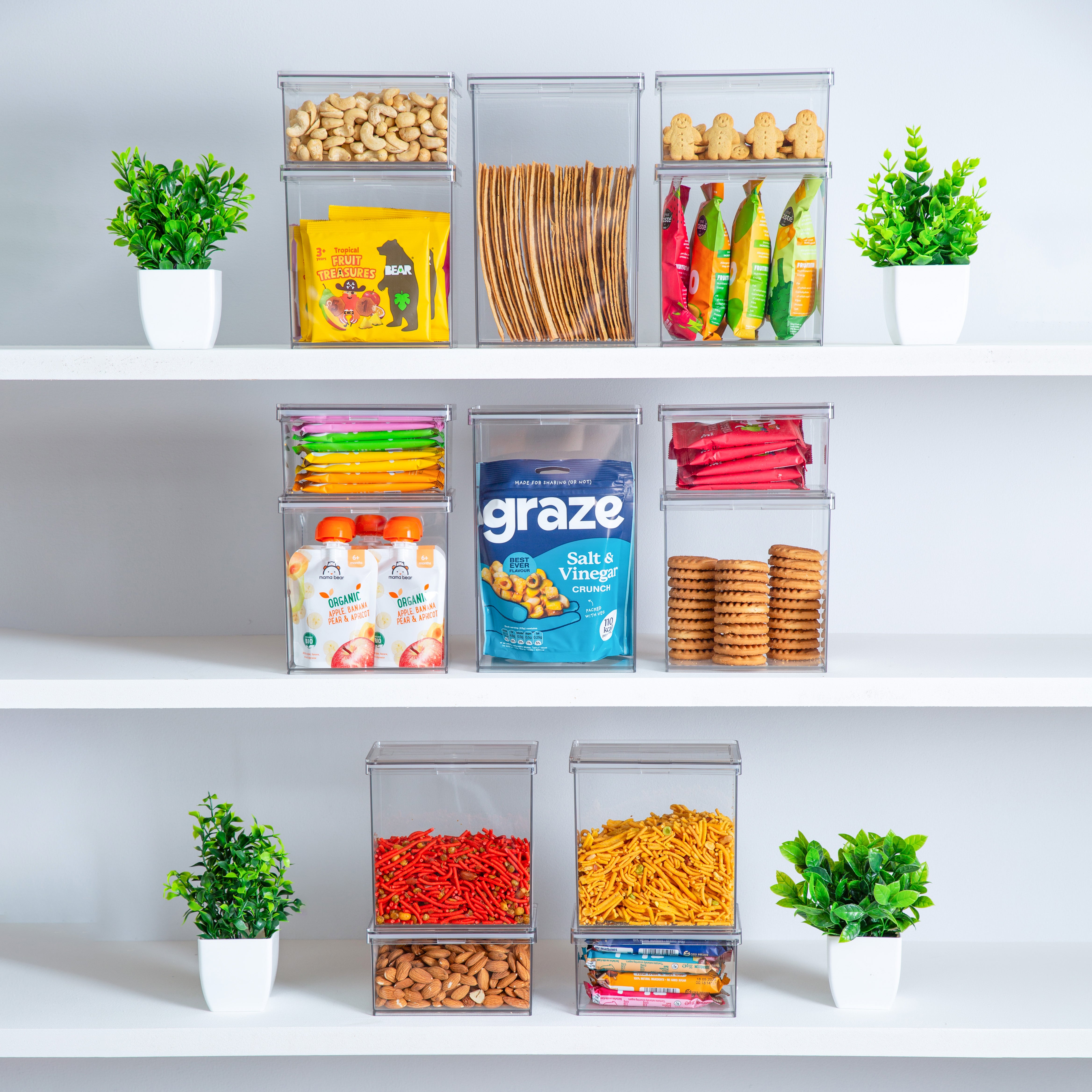 Graze snack packaging in airtight food canisters on a shelf with decorative plants and snacks.