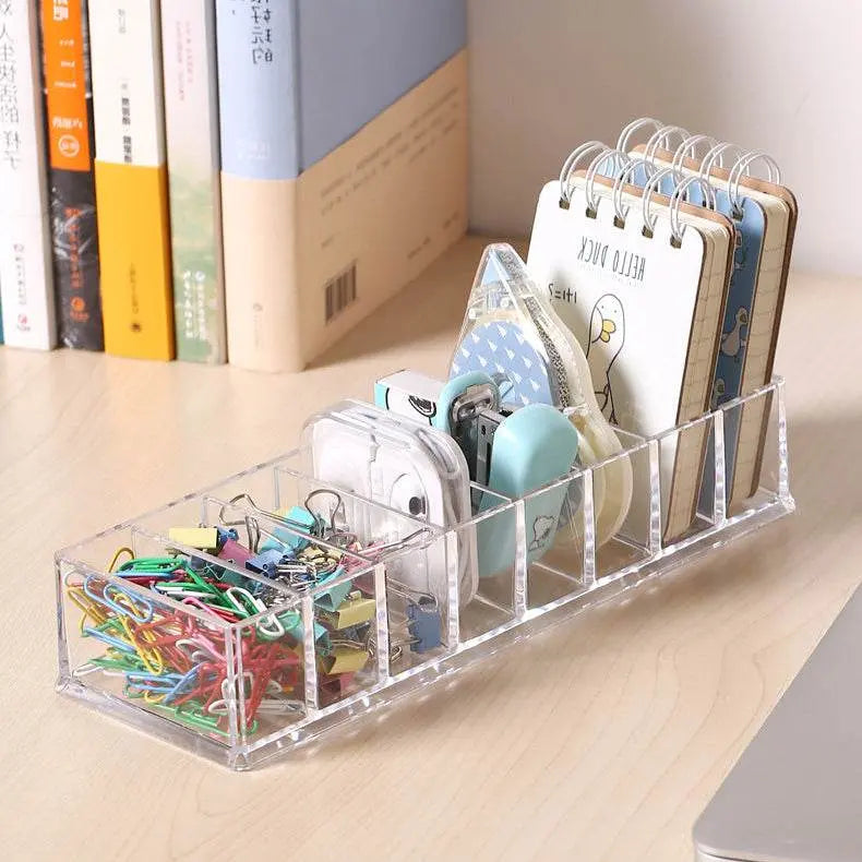 Clear acrylic desk organizer with stationery items on a wooden surface.