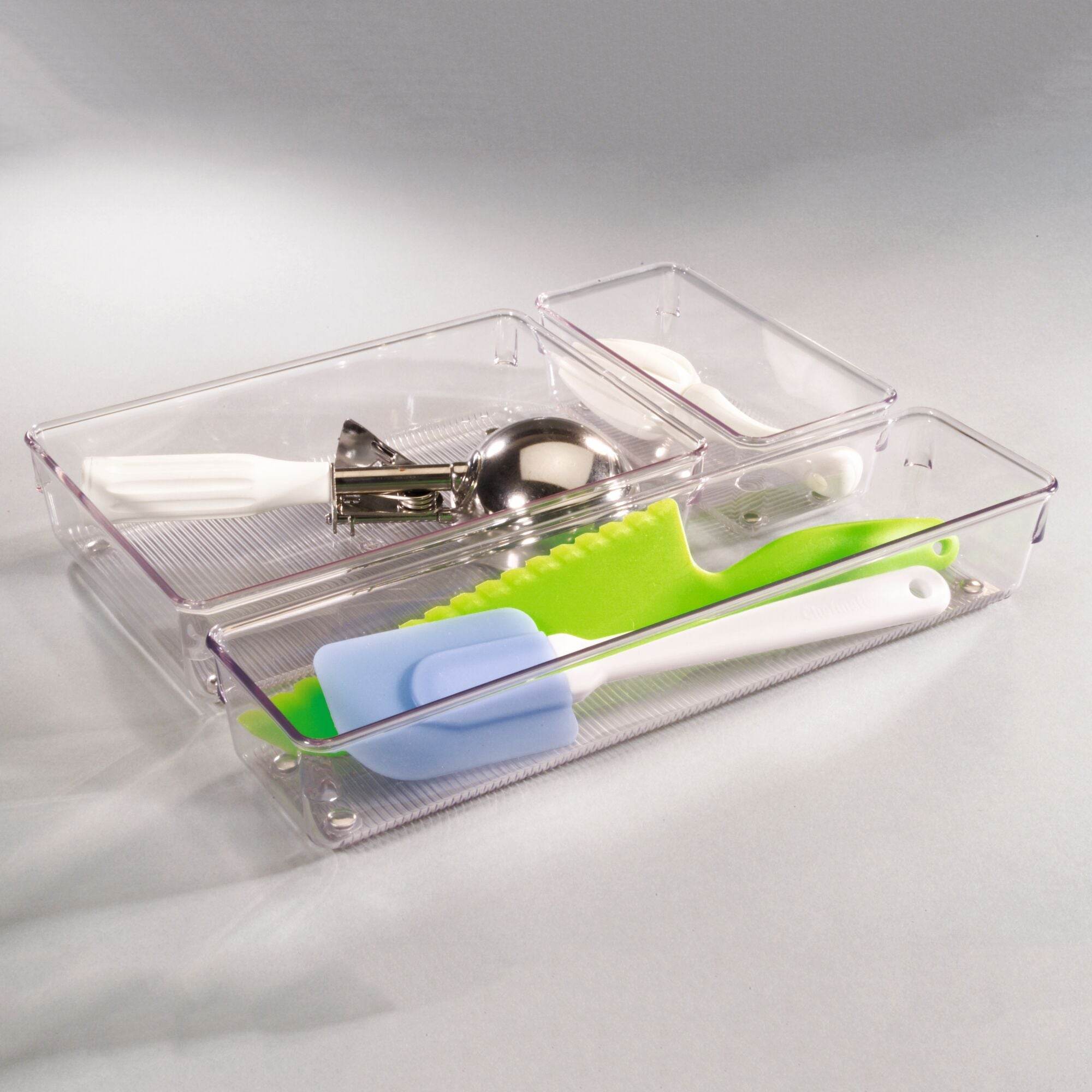 Clear plastic kitchen utensil holder with various tools on a light gray background