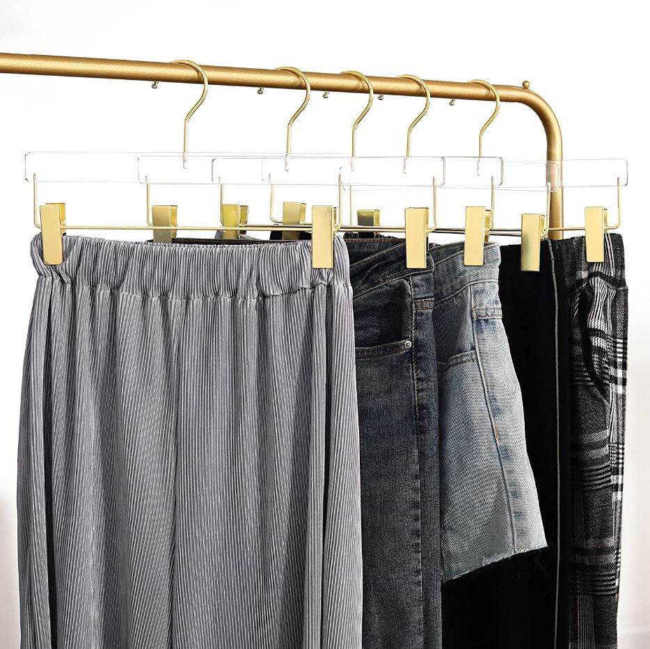 Clothing items on Acrylic hangers on a gold rack against a white background