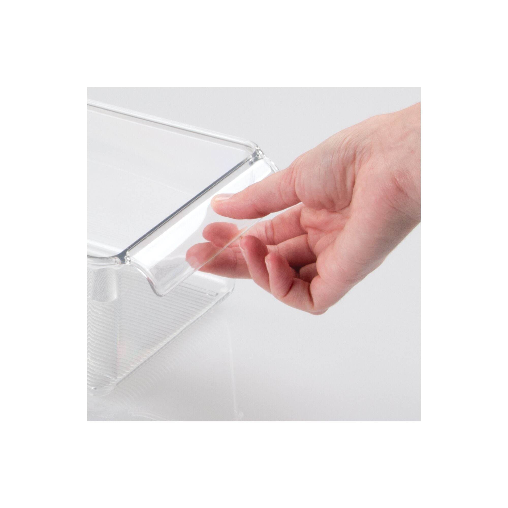 Clear plastic corner protector on a white background with a hand for scale.