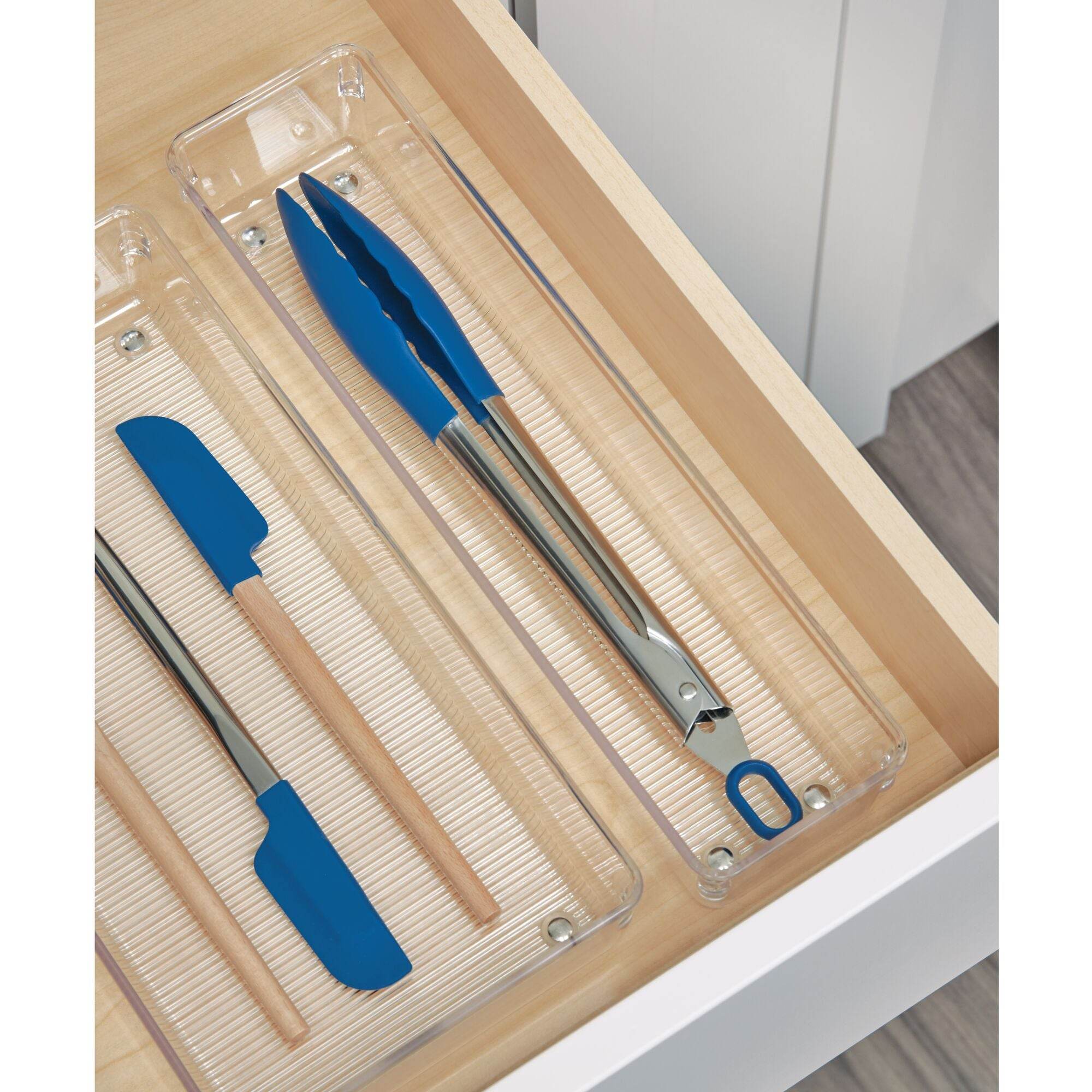 iDesign Linus drawer organisers with spatula and tongue inside them on a wooden surface.